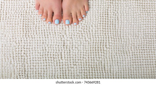 Woman Feet With A Blue Pedicure Standing On A White Bathroom Rug