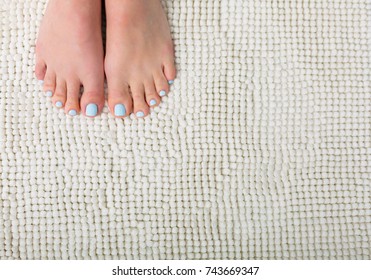 Woman Feet With A Blue Pedicure Standing On A White Bathroom Rug