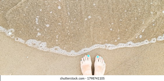 Woman Feet With Blue, Pink Toenails On Natural Beach Sand