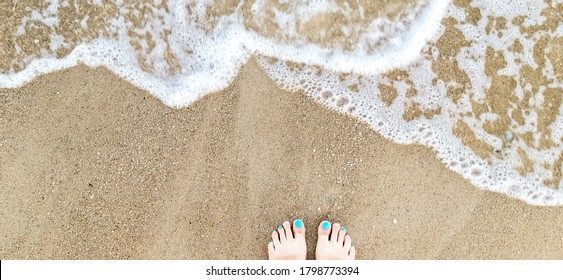 Woman Feet With Blue, Pink Toenails On Natural Beach Sand