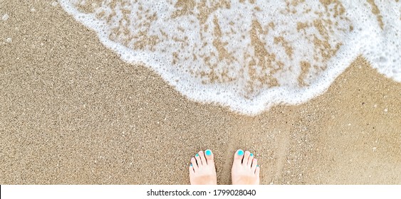 Woman Feet With Blue, Pink Toenails On Natural Beach Sand