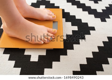 Woman feet with colorful toes pedicure standing on electric scales. Diet concept
