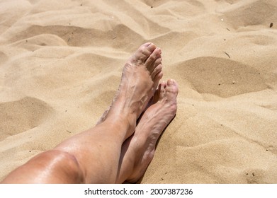 Woman feet crossed on the sandy beach, Guardamar of the Segura, Spain, enjoying vacations in the fine sands of this place