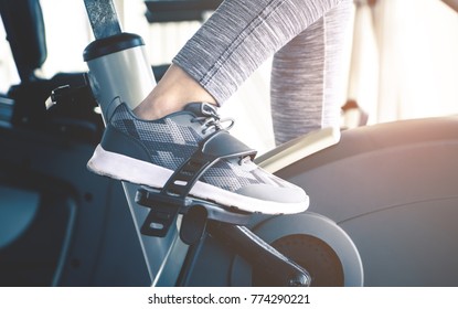 Woman feet is cycling on fitness bike machine