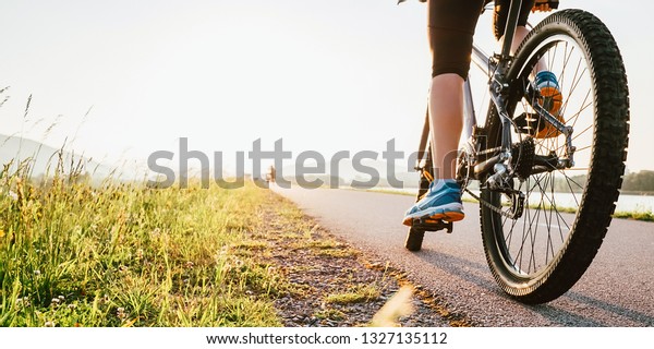 Woman feet on\
bycikle pedal in sunset\
light