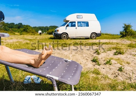 Woman feet on deck chair. Female relaxing enjoying sun on sunny summer day in front of rv campervan..