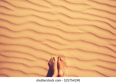woman feet on golden sandy beach. holiday concept. top view