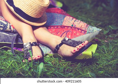 Woman Feet On Grass In Flat Summer Sandals Lean On Pillows  Hat Lay On Legs 