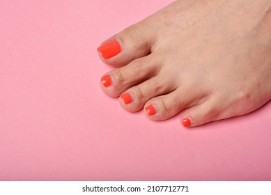 Woman feet on pink background, Red nail pedicure, Beauty salon concept.