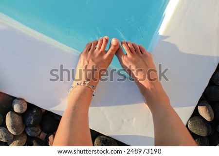Woman feet on swimming pool