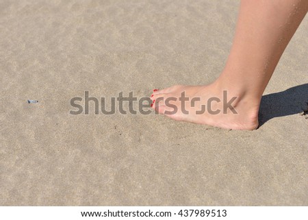 Woman feet with red pedicure walking on the hot sand of the beach. Summer holiday.