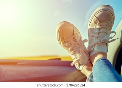 Woman Feet In Sneakers On A Car Dashboard. Roadtrip And Freedom Travel Concept