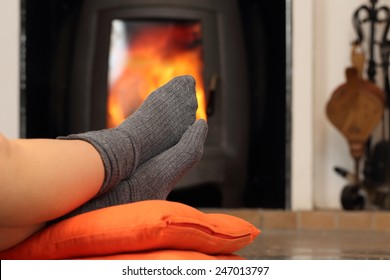 Woman Feet With Socks Resting Near Fire Place With A Warmth Background