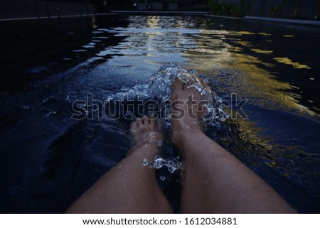 Woman feet in the swimming pool and splash water