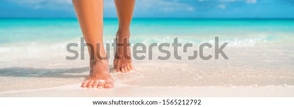 Woman feet walking on caribbean beach barefoot\
closeup of foot coming out of water after swim banner panorama.\
Honeymoon travel\
vacation,