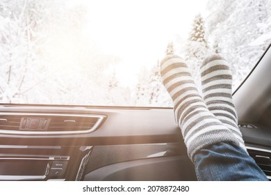 Woman Feet In Warm Woolen Socks On Car Dashboard Over Snow View. Winter Travel Concept.