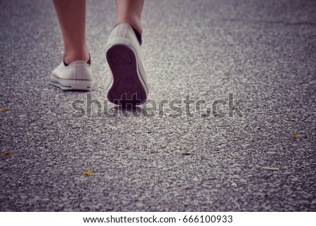 Woman feet wearing white sneakers walking on the street, space for text, Vintage color tone