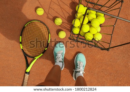 Woman feets, racket and tennis balls on clay court