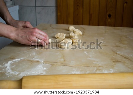 Woman female hands cutting raw dough on kitchen table, preparing for baking