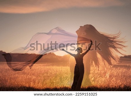 woman in the field feeling free at peace in nature holding fabric cloth blowing in the wind.