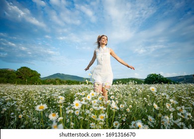 Woman in a field with flowers. Beautiful girl in a field with daisies.