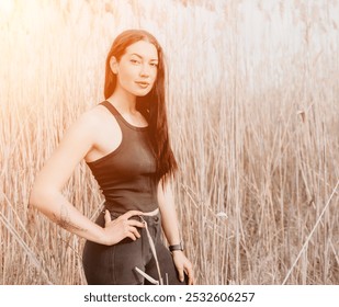 Woman, Field, Sunset: A young woman poses in a field of tall grass, bathed in the golden light of sunset. - Powered by Shutterstock