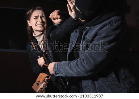 Woman fighting with thief while he trying to steal her bag outdoors at night. Self defense concept