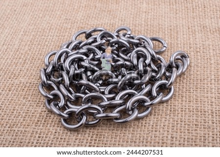 Woman figurine on steel chains on a textured surface on display