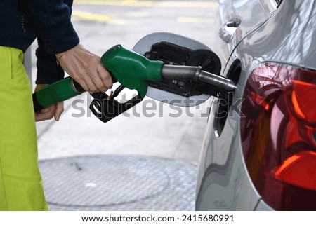 Woman filling a car with gasoline at a gas station