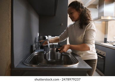 A woman filling a cooking pot with water at a kitchen sink in a contemporary kitchen. Clean and organized environment. - Powered by Shutterstock