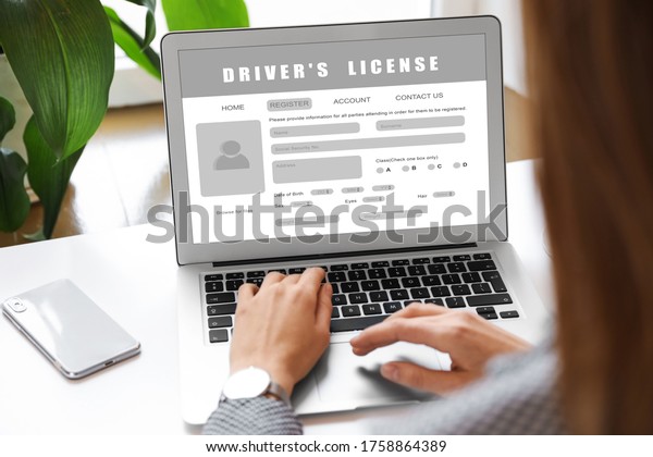 Woman filling in driver\'s license form online on\
website using laptop,\
closeup