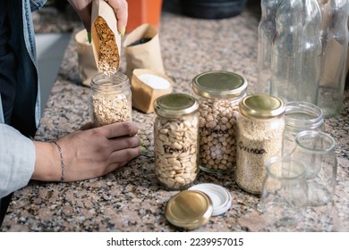 Woman filling empty recycled jar with bulk food at home. Sustainability and eco friendly concept. Close up, unrecognizable person - Powered by Shutterstock