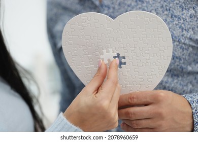 Woman filling empty space with missing piece of white heart puzzle - Shutterstock ID 2078960659