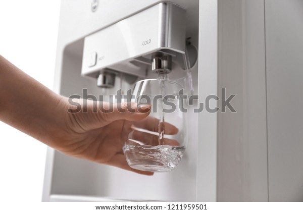 Woman\
filling glass with water from cooler,\
closeup