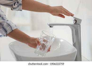 Woman Filling Glass With Water From Faucet Over Sink, Closeup