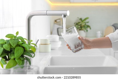 Woman filling glass with water from tap in kitchen, closeup - Powered by Shutterstock