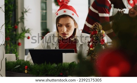 Woman filling paperwork in Christmas decorated office, perturbed by noisy coworkers discussing in background. Employee trying to concentrate on job while colleagues take shift break