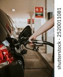 Woman filling petrol at a gas station. Woman at petrol station filling gas into a car. Self service petrol station. Car getting gas by a woman at a petrol station.