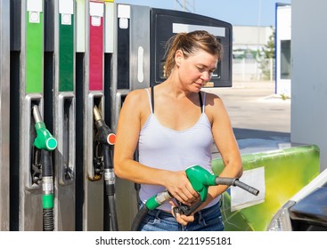 Woman Filling Up Tank Of Her Car With Gasoline In Gas Station