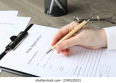 Woman filling visa application form for immigration at table, closeup