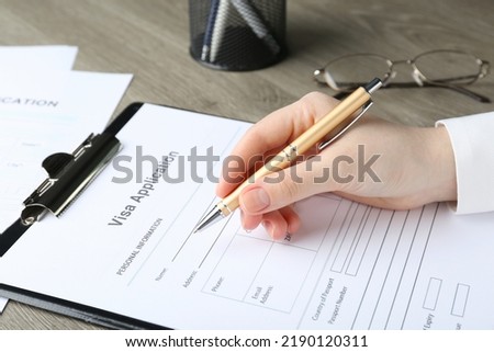 Woman filling visa application form for immigration at table, closeup