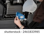 Woman filling water tank in car engine, close up of hands