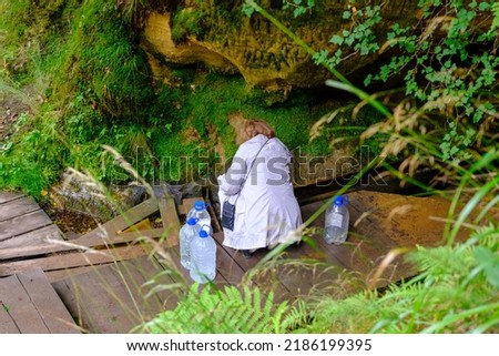 A woman fills five-liter containers with natural drinking water at a water source in the Gauja National Park, Latvia.