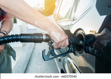 Woman Fills Gasoil Into Her Car At A Gas Station. Woman Wearing Plastic Gloves