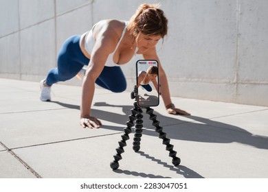 Woman film herself on mobile phone and live streaming her fitness workout on social media