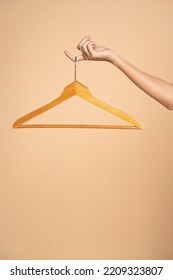 Woman finger holding empty hanger on a beige studio background. Mock up for design