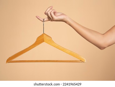 Woman finger holding empty hanger on a beige studio background. Mock up for design