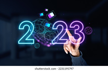 Woman finger touching neon 2023 year numbers, digital hologram of spheres and data blocks with sphere flying. Concept of virtual world and connection