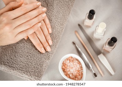 Woman fingers with beautiful nails on brown towel with manicure tools. Close up of woman hands on a towel after manicure. Top view of beautiful natural manicured woman hands.