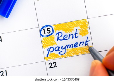 Woman Fingers With Pen Writing Reminder Rent Payment In Calendar. Close-up.
